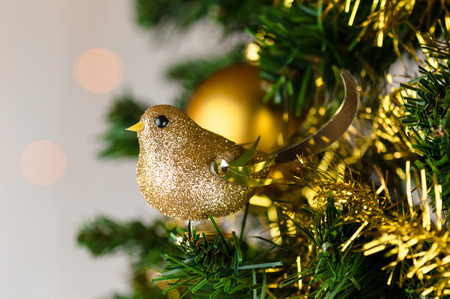 Festive Christmas close up of tree decorated with gold glitter robin, tinsel and bauble.の写真素材