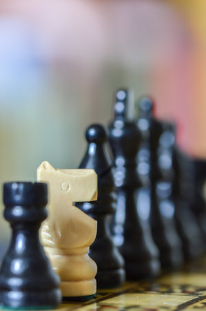 Close up of black chess pieces with focus on an out of place white knight, the rest deliberately out of focus with blurred background. Racial concept. Copy space.のeditorial素材
