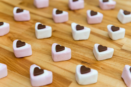 Heart shaped sweets on a wooden table. Chocolate and marshmallow. Naughty treat for Valentines day.