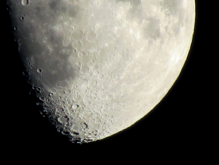 Bottom of the moon in part shadow in the black night sky showing details of the lunar surface.