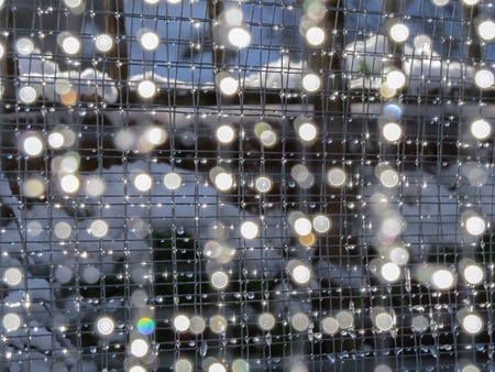 Background of weld mesh with melting snow creating droplets of sparkling water and round bokeh....