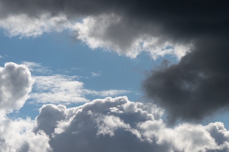 Billowing clouds with blue sky. Moody stormy weather with both dark grey clouds and contrasting...