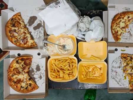 Overhead view of takeaway pizza meal partly eaten. Authentic home scene.