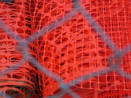 Orange construction fence seen through metal chain-linked fenceの写真素材