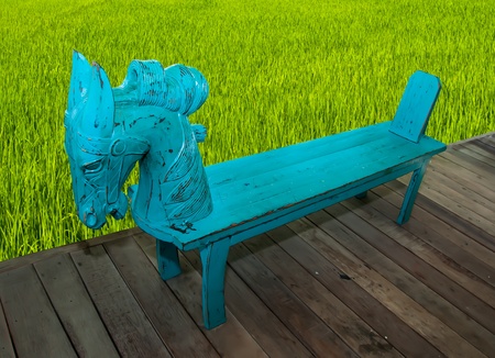 Wooden bench head horse on field rice backgroundの写真素材