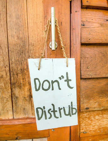 " Do Not Disturbâ  sign hanger on wooden doorの写真素材