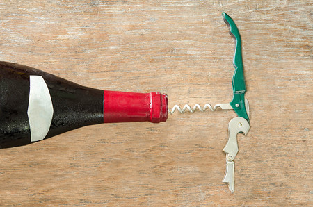 Red wine bottle with opener on wood backgroundの写真素材