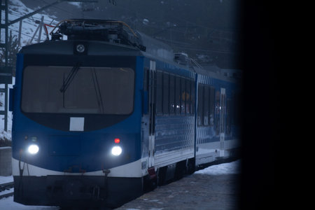 Blue train on snowy tracks in a winter landscape.の写真素材