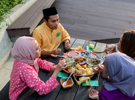 Top view of Muslim family enjoying a variety of traditional Malay cuisines on a circular tray on a black table, at end of Ramadan Mubarak Kareemの写真素材