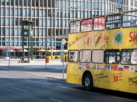 BERLIN, GERMANY - AUGUST 3, 2018: Yellow Tourist Bus At Famous Potsdamer Platz Square With Clock In Background In Berlin, Germanyのeditorial素材