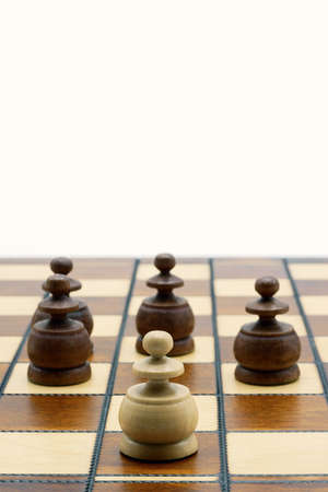 Underdog Concept: One White Pawn Standing Against Four Black Pawns On A Chess Board, With Copy Spaceの写真素材