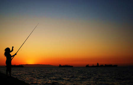 women fishing at sunsetの写真素材