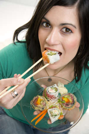 A 29 year old woman takes a bite of a Sushi Rollの写真素材