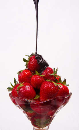 Chocolate sauce hits the berries in a glass parfait containerの写真素材
