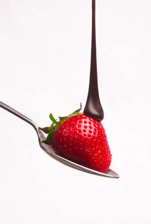 Chocolate sauce hits the berry on a spoonの写真素材