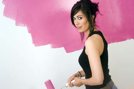 A brunette woman paints the wall of her apartmentの写真素材