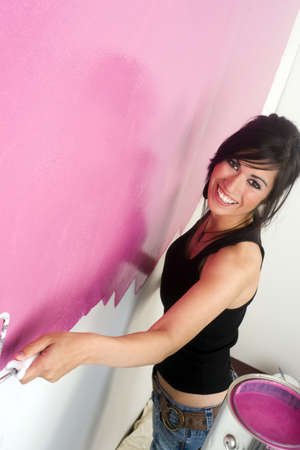 A brunette woman paints the wall of her apartmentの写真素材