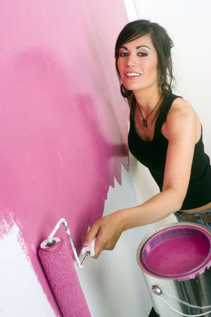 A brunette woman paints the wall of her apartmentの写真素材