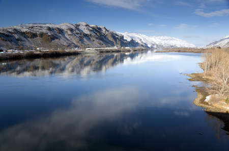Columbia River Flows After Fresh Snow beneath Mountain Peaks and Businessesの写真素材