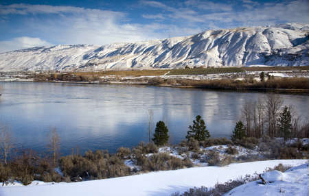 Columbia River Flows After Fresh Snow beneath Mountain Peaks and Fruit Orchardsの写真素材