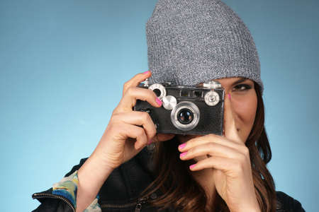 Hip Attractive Woman in Beanie Cap Snaps a Picture of Viewer with Vintage Camera