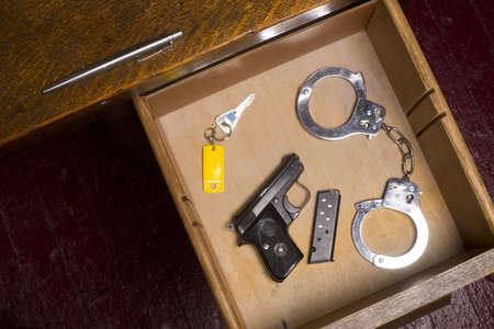 A desk housing pen, gun, key, and handcuffsの写真素材