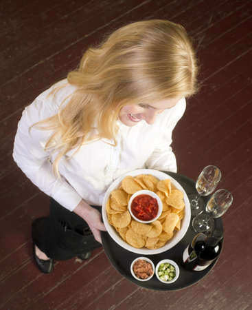 A Young Attractive Female Server Brings Wine and Appetizer Food Trayの写真素材