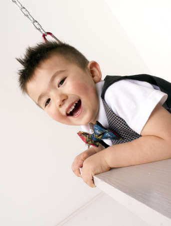 Fun loving young child playing swinging smilingの写真素材