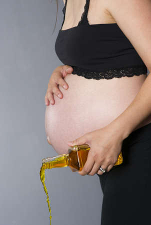 Vertical composition of woman pouring out a bottle of hard whiskey during pregnancyの写真素材