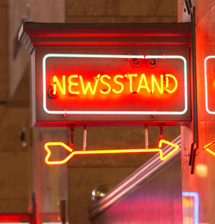 A red neon sign points the way to the news standの写真素材