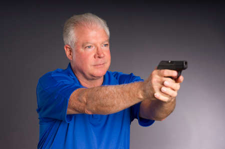 Man points small caliber semi automatic handgun to off camera rightの写真素材