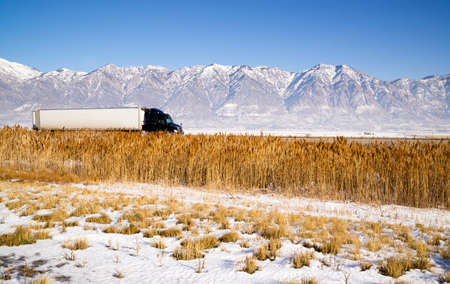 Snow Covered Mountains Behind Lakeside Highway PLant Growth Utah Landscapeの写真素材