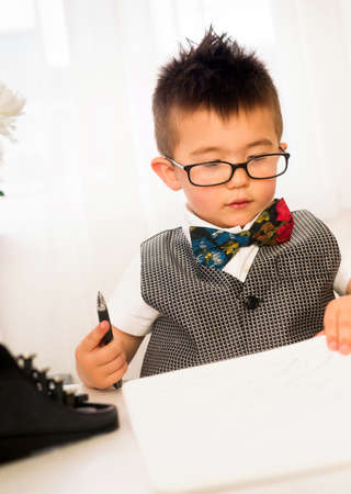 Male child plays like a business man at his desk