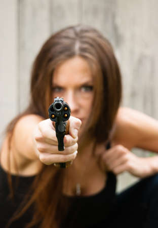 Woman crouches and prepares to fire second shot at assailant の写真素材