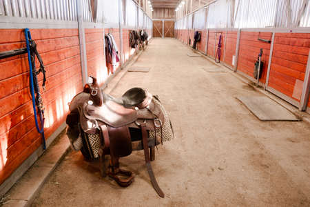 A saddle waits to be mounted on horses back at stablesのeditorial素材