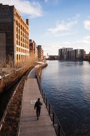 Vertical composition of man walking on a sunny spring day along the boardwalk in Milwaukeeの写真素材