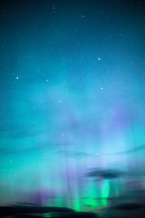 The Northern Lights emerge through the clouds in remote Alaskaの写真素材