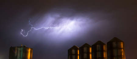 A storm passes over large metal containers releasing electrical charge