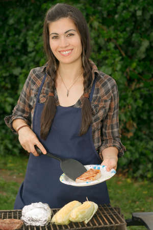 Female plates up the food at the backyard cook outの写真素材