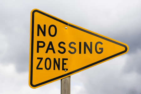 a reflective sign bolted to a post says no passing zoneの写真素材