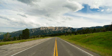 A well worn two lane road leads to a vanishing point in the mountainsの写真素材