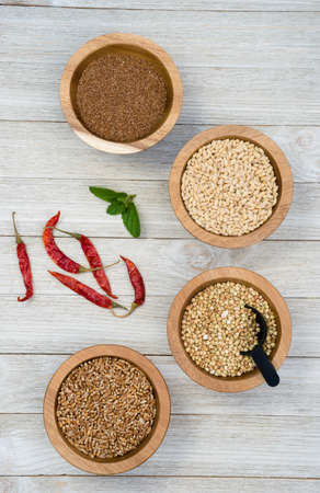 Wheat Berries Buckwheat Groats Pearl Barley Farrow in Bowls with Red Peppers on the sideの写真素材
