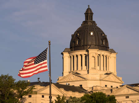The American Flag waves in front of the capitol dome in Pierre, SDの写真素材