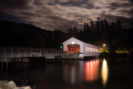 Lights glow and reflect in the water night scene Lowell Covered Bridge