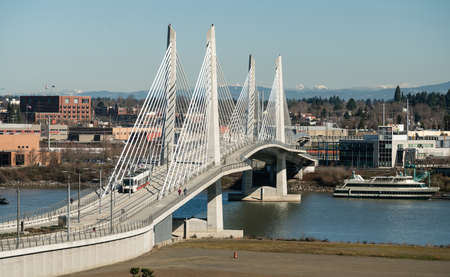 It's a clear day in Portland Oregon at Tilikum Crossing as people traverse the river with the Cascade Mountain Rangeの写真素材