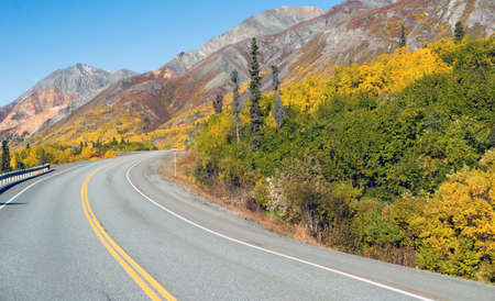 The road winds around the mountain base revealing a photo opportunity sign scenic wild area of Alaskaの写真素材