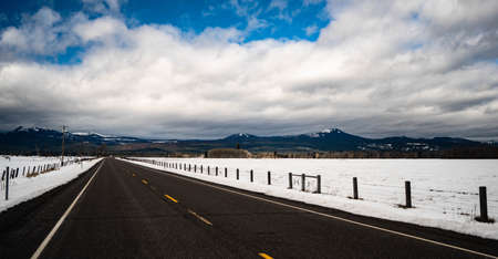 The road is clear passing snow covered range land near Fort Klamath Oregonの写真素材