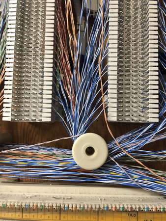 Small diameter multi color wires run around spools mounted to boards in the phone room