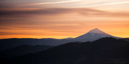 The sun slips down below the horizon and leaves rich saturated orange color around Mt. McLoughlin in the Cascade Rangeの写真素材