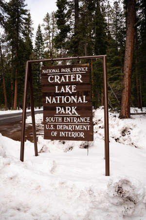 The sign rocks and sways back and forth in the wind at Crater Lake NPの写真素材